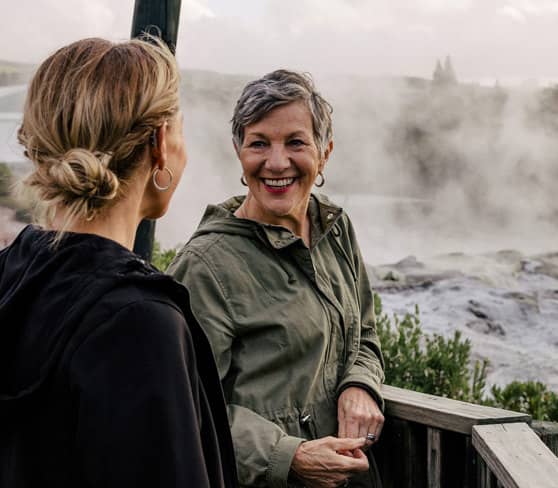 Two women enjoying the view of steaming geysers in Rotorua.