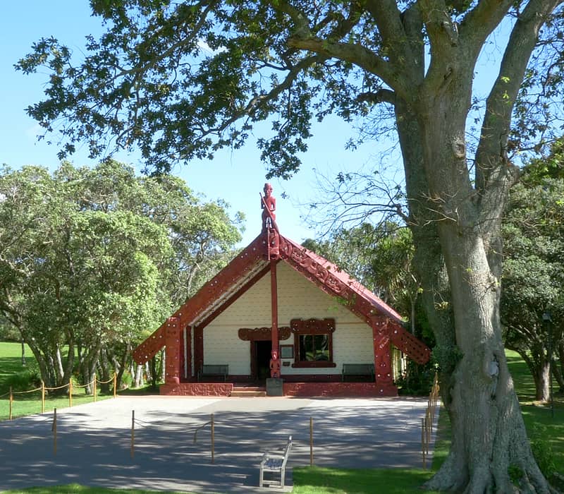 Maori meeting house Te Whare Runanga surrounded by trees and grass at Waitangi Treaty Grounds.