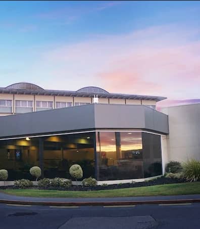 Hotel building with large windows at sunset under a colorful sky.