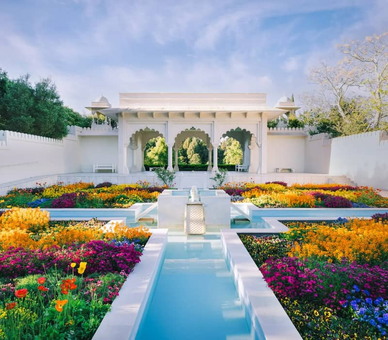 Indian Charbagh Garden with colorful flowers, white pavilion, and water canals on a clear day.