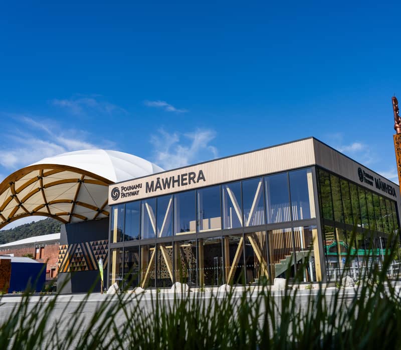 A giant, hyper-realistic sculpture of the Māori warrior chief Tūhuru, standing over twice life-size and wearing traditional woven garments, inside the Māwhera experience centre.