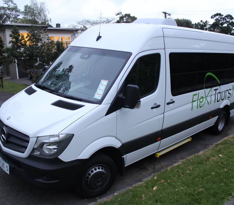 White FlexiToursNZ Mercedes van parked on suburban street at dusk