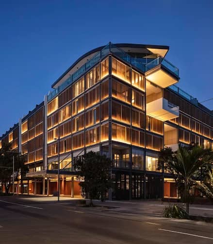 Modern hotel building with glowing lights and balconies at night on a city street.