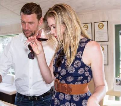 Man and woman smelling red wine during an indoor wine tasting event.