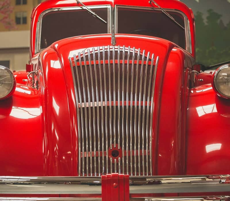Front view of a red 1940 Dodge Airflow tanker vintage car with chrome grille and round headlights.