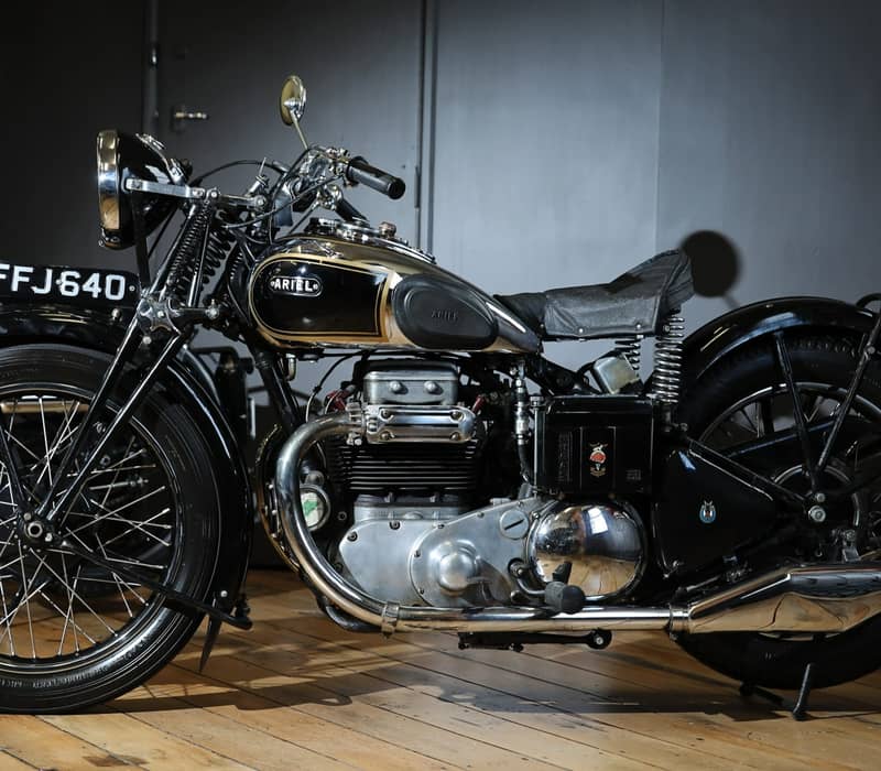 Side view of a black 1939 Ariel Square Four vintage motorcycle indoors.