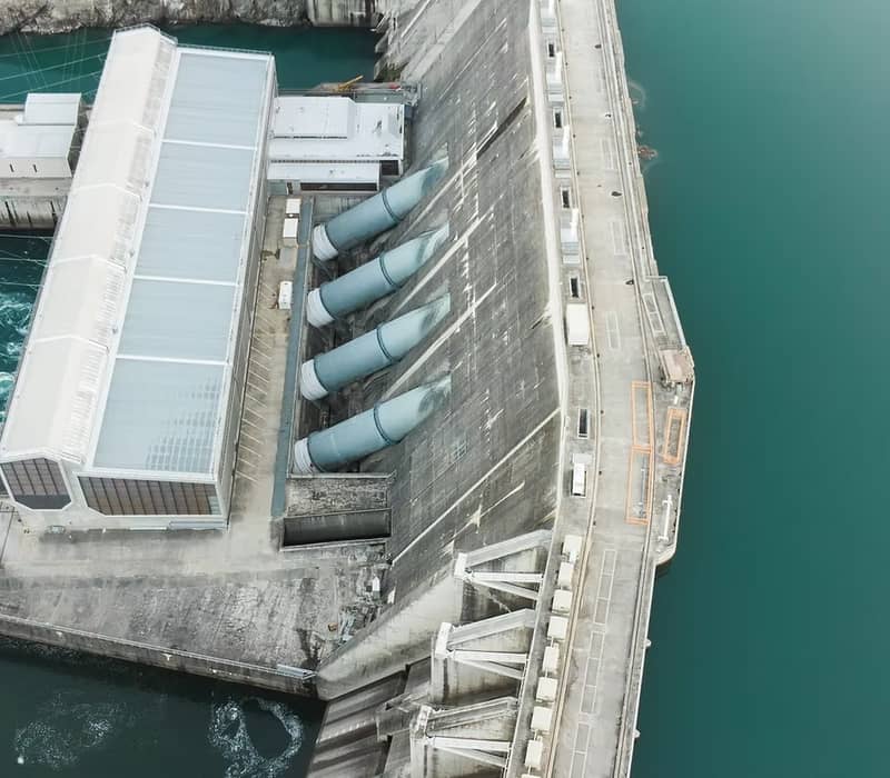 Aerial view of Clyde Dam with water flowing through large pipes and concrete structure.