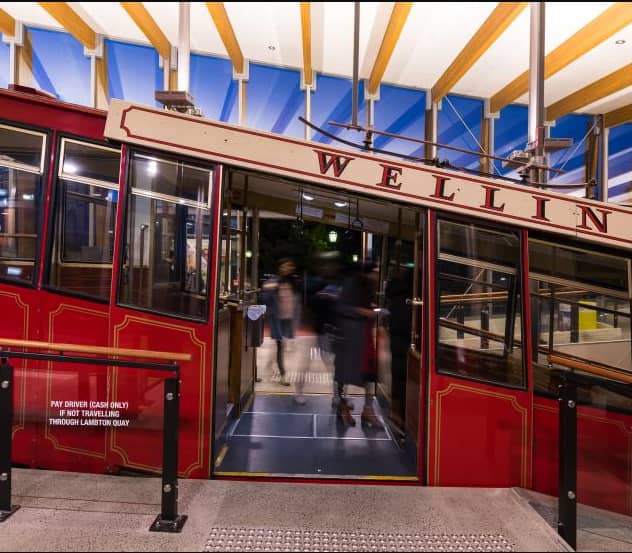 Red Wellington Cable Car at station with passengers boarding at night under glass roof