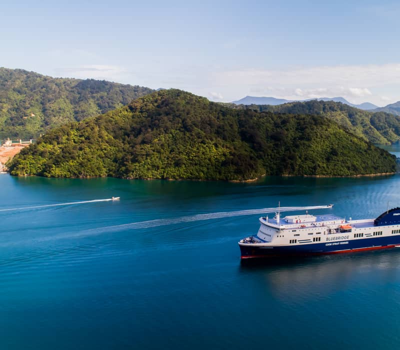 Bluebridge ferry crossing blue sea near green islands on a clear sky day