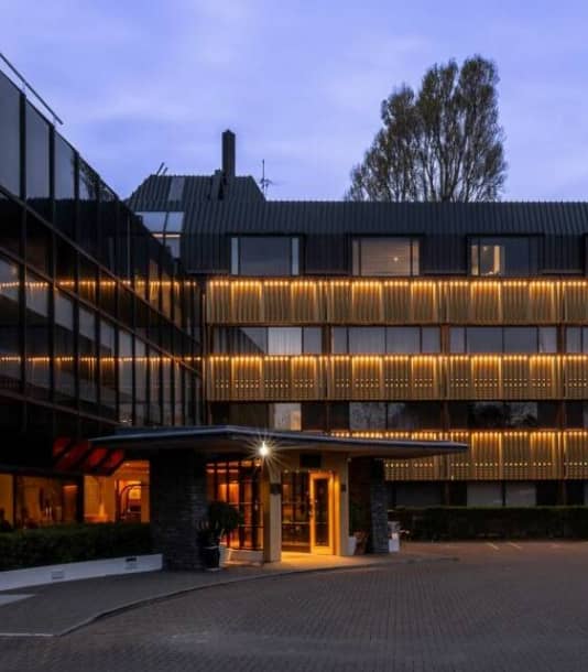 Modern hotel building with lit exterior and entrance at dusk