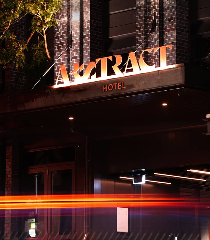 Hotel bedroom with double bed, two pillows, blue walls, window with curtains, and wall art.