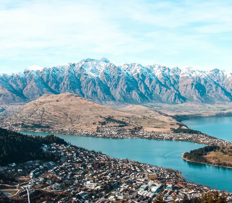 Elevated view of Queenstown and Lake Wakatipu with snow-capped mountains in the background and a luge track in the foreground