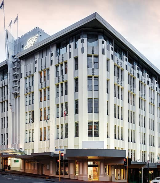 Large multi-story hotel building on a city street corner with flags and windows