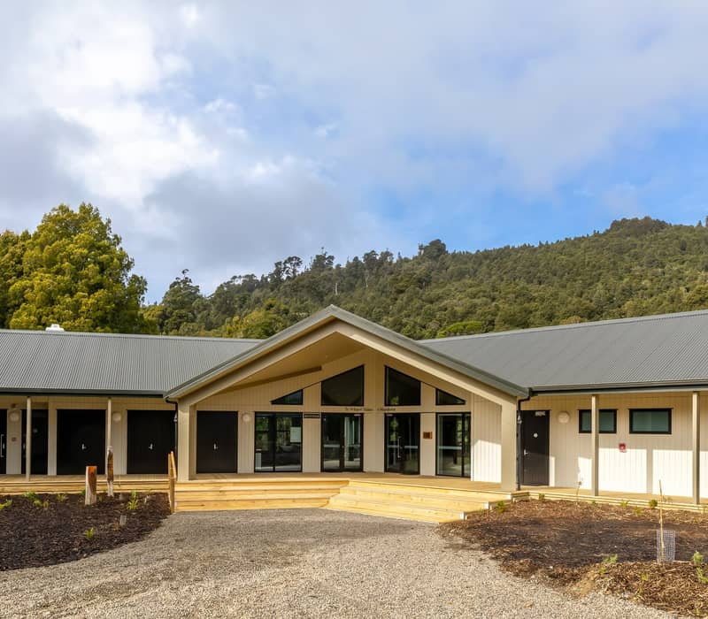 Entrance to Pukaha Mount Bruce Wildlife Centre with forested hills and cloudy sky in the background.