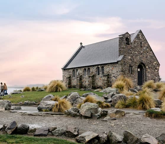 Church of the Good Shepherd by Lake Tekapo at sunset with stone path and tussock grass.