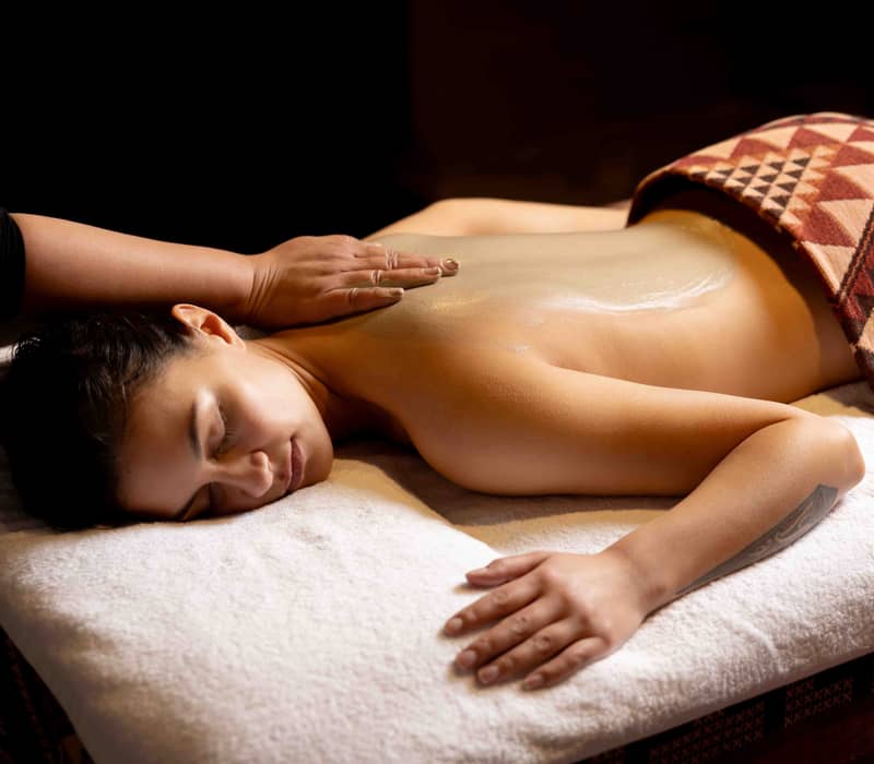 Woman receiving a relaxing oil massage on her back at a spa.