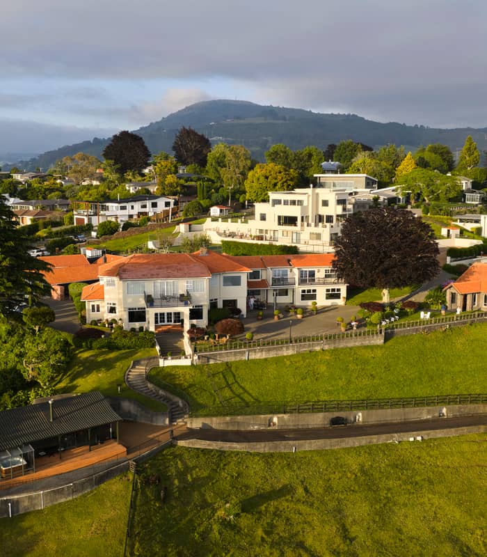 Resort accommodation on a green hill with trees and buildings under sunlight.