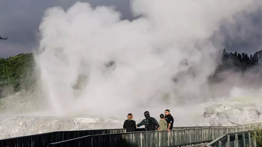 Visitors observing steam from a geyser in Rotorua.