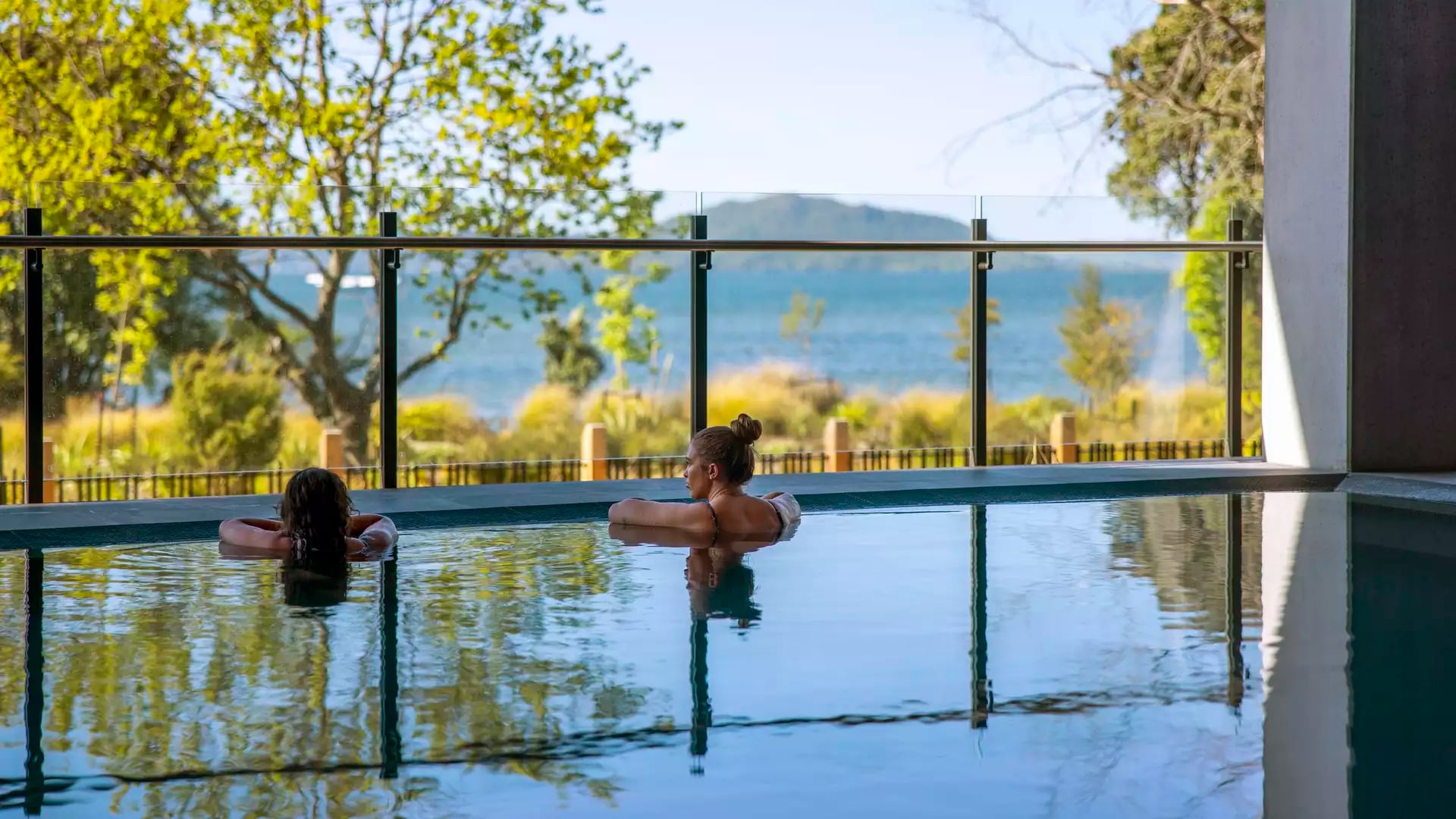People bathing in pools at Wai Ariki spa and enjoying view of lake.