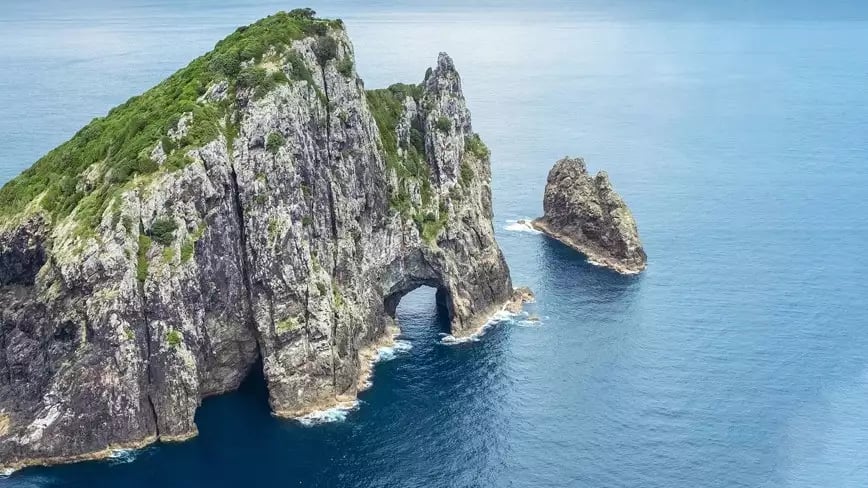 Hole in the Rock, Bay of Islands, New Zealand surrounded by blue sea.