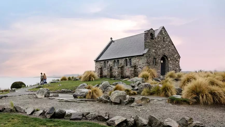 Church of the Good Shepherd by Lake Tekapo at sunset with stone path and tussock grass.
