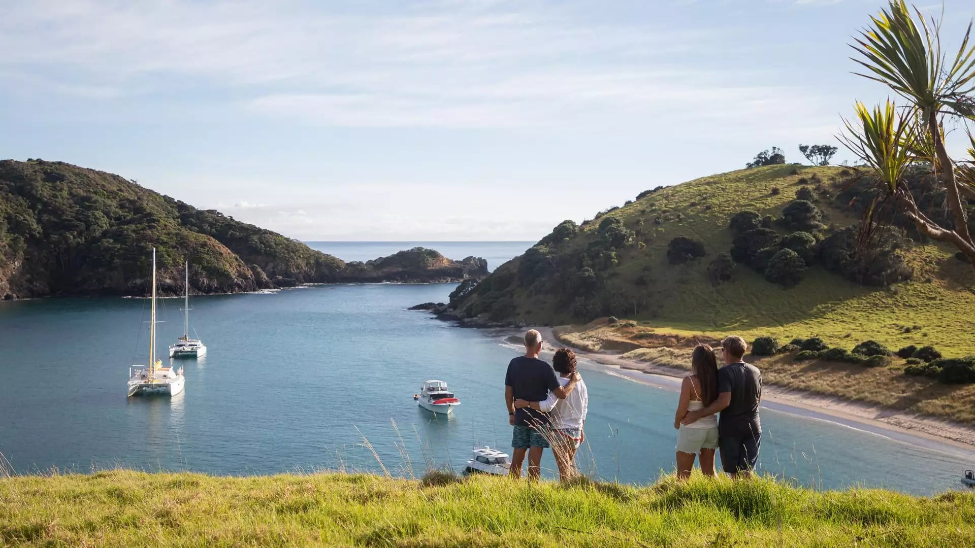 Couples overlooking a calm bay with boats and green hills in the Bay of Islands.