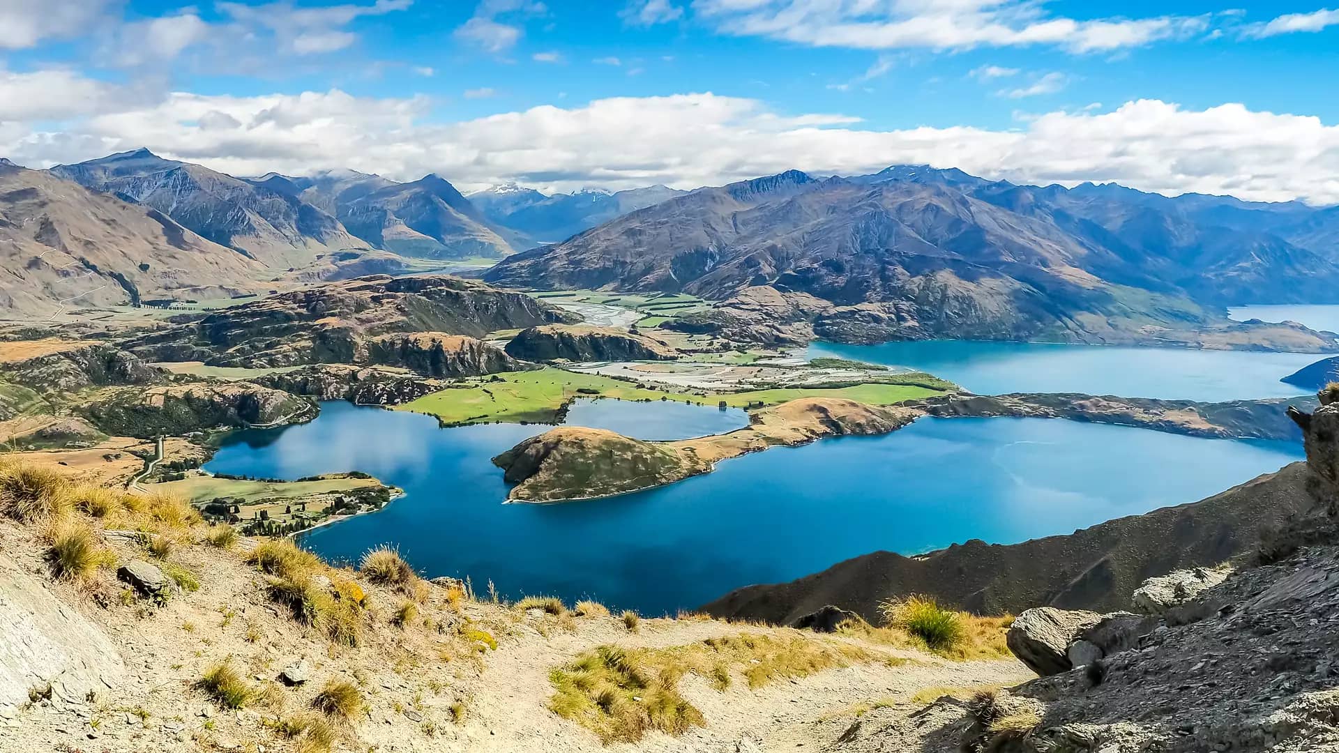 Panoramic view of Lake Wanaka with mountains and blue sky in the background. Credit: Fine Tours Group
