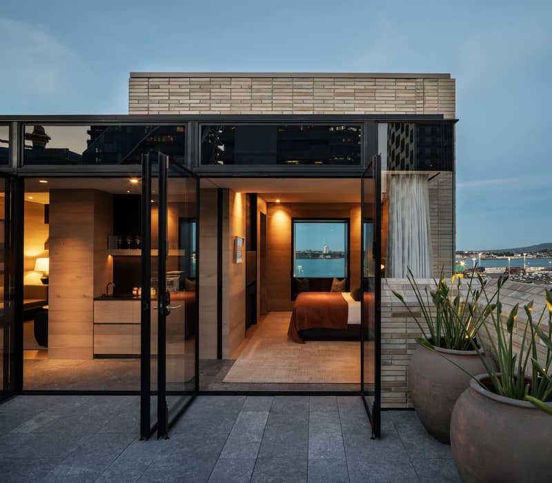 Luxury rooftop hotel suite in Auckland with an open terrace, harbor views, and modern timber-clad interiors.