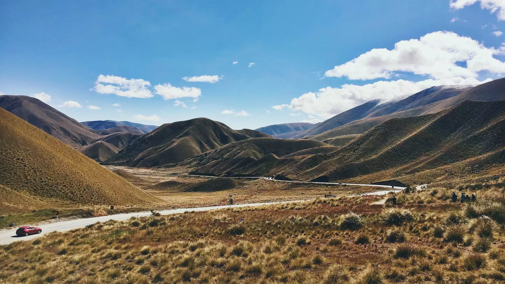 Mountainous landscape with winding road under a clear blue sky and scattered clouds