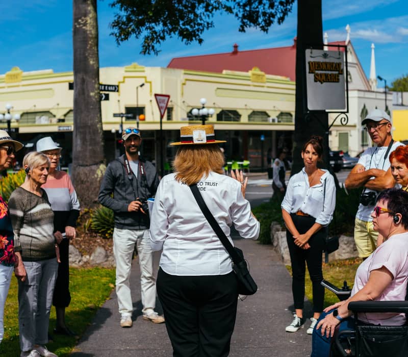 Group of people listening to a guide on an outdoor walking tour in a city park.