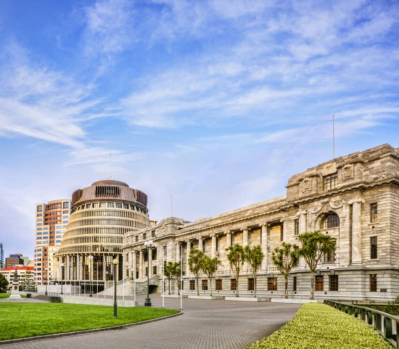 Iconic parliament buildings in Wellington with blue sky and greenery.