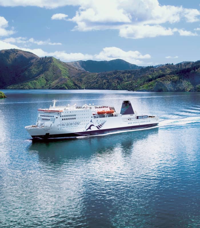 Interislander ferry sailing on blue water with green hills and clouded sky