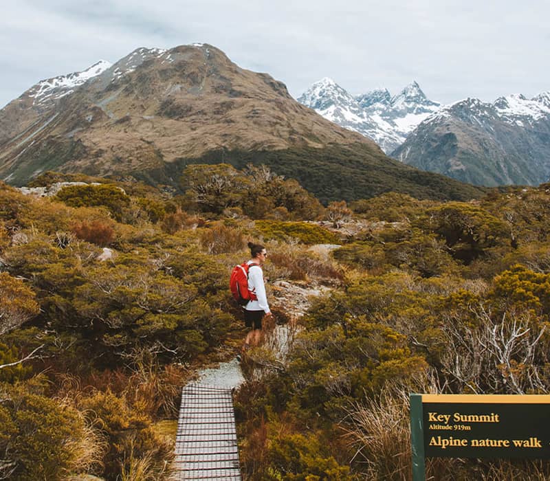 Hiker on alpine trail at Key Summit with mountains and snow in the background