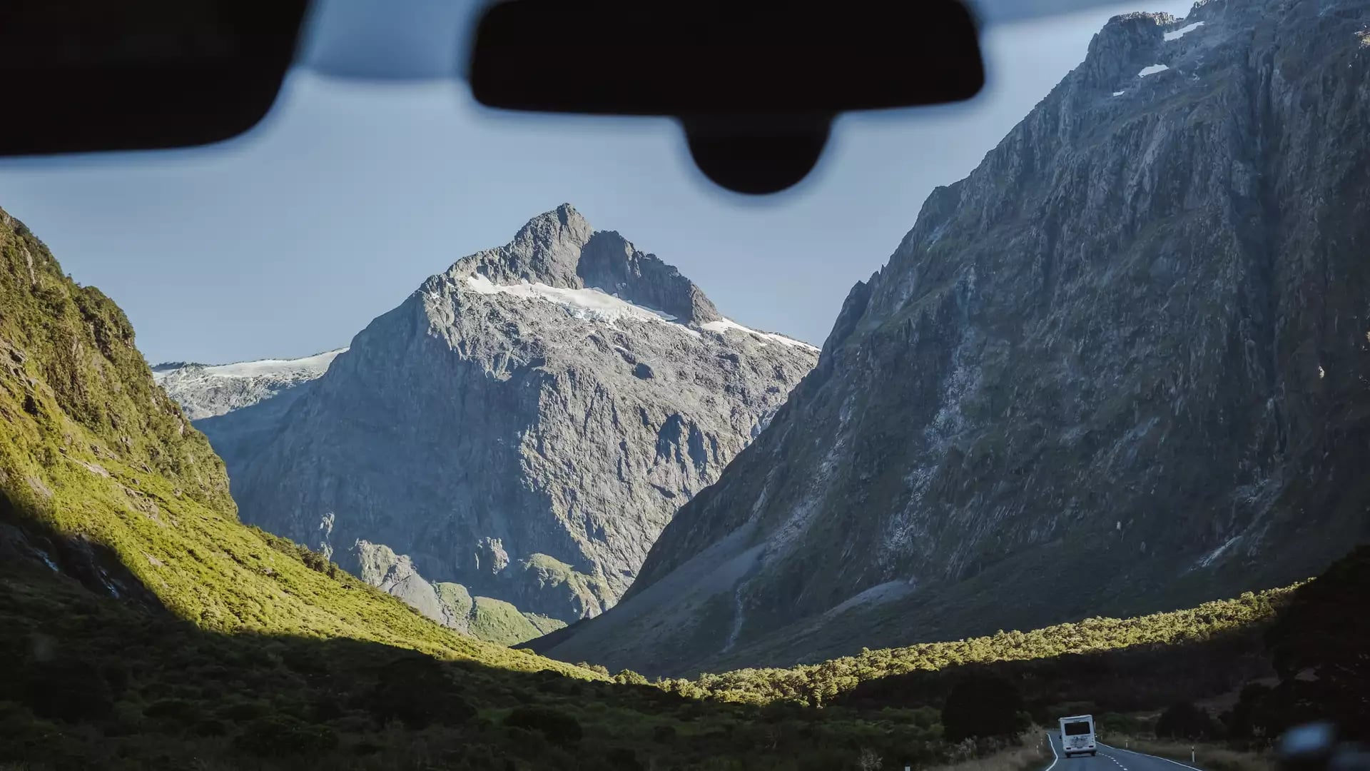 View of mountains and valley through front windshield of a van on a sunny day